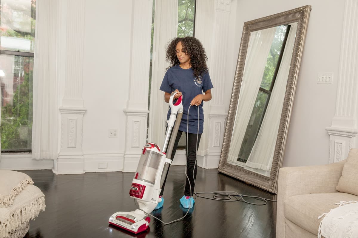A cleaner vacuuming the floor of a bright living room
