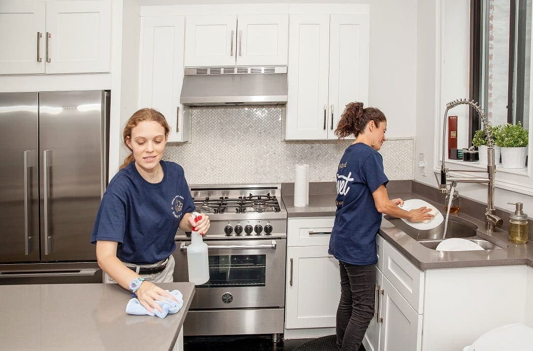 Two cleaners working a kitchen, cropped wide